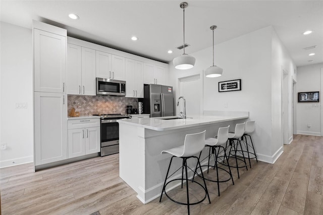 kitchen featuring visible vents, backsplash, appliances with stainless steel finishes, a sink, and a kitchen breakfast bar