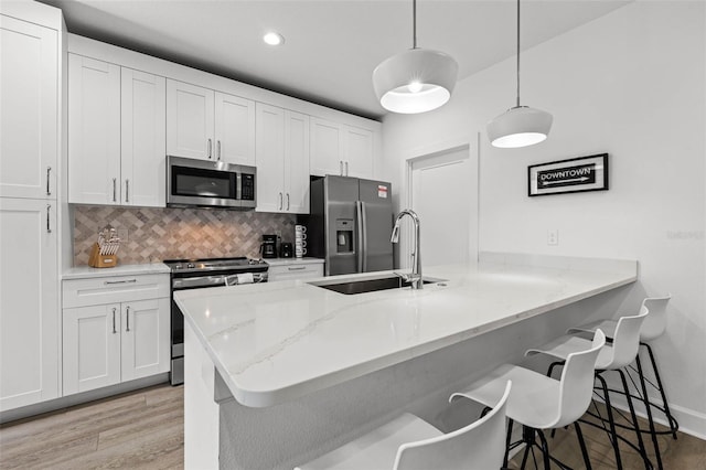 kitchen featuring tasteful backsplash, a breakfast bar area, a peninsula, stainless steel appliances, and a sink