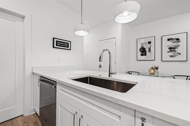 kitchen featuring a sink, light wood-style flooring, light stone counters, and stainless steel dishwasher