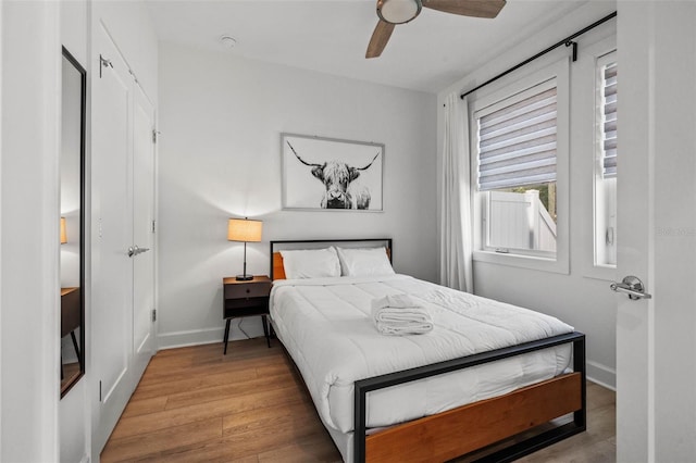 bedroom featuring ceiling fan, baseboards, and wood finished floors