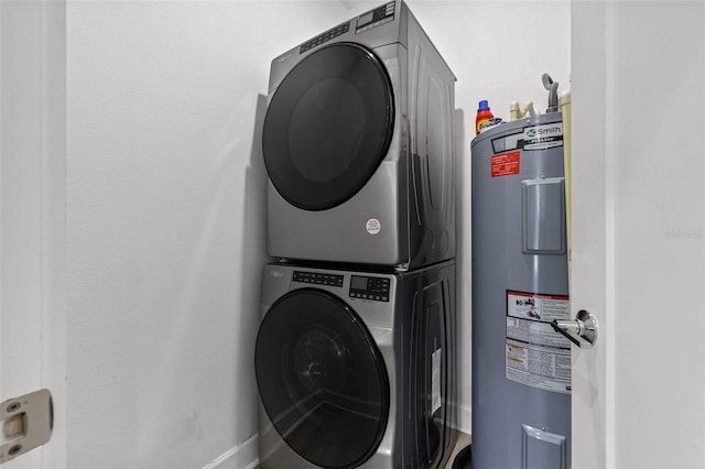 clothes washing area featuring laundry area, electric water heater, and stacked washing maching and dryer