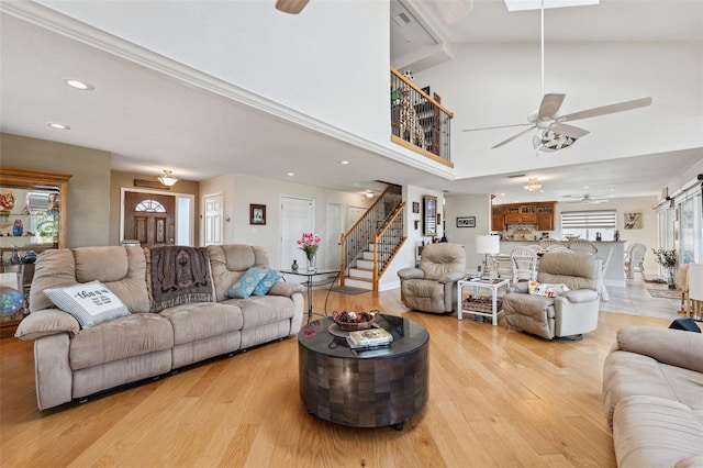 living area featuring recessed lighting, a barn door, a ceiling fan, light wood-type flooring, and stairs