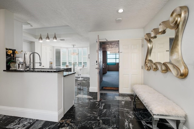 interior space featuring marble finish floor, baseboards, stainless steel refrigerator with ice dispenser, and a textured ceiling