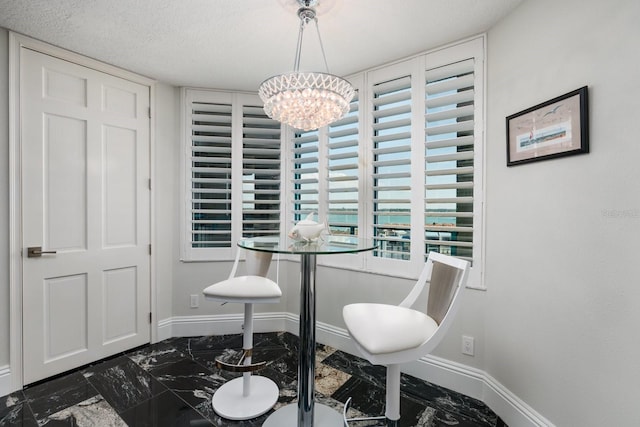 dining room with marble finish floor, a notable chandelier, a textured ceiling, and baseboards