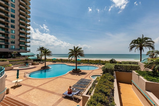 community pool featuring a community hot tub, a water view, and a patio