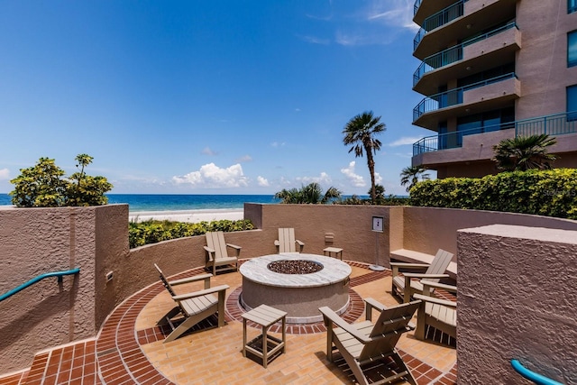 view of patio / terrace with an outdoor fire pit, a water view, and a view of the beach