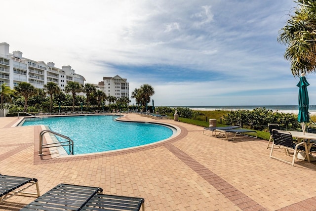 community pool with a water view and a patio area