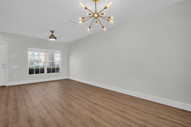 unfurnished living room with ceiling fan with notable chandelier, visible vents, baseboards, and wood finished floors