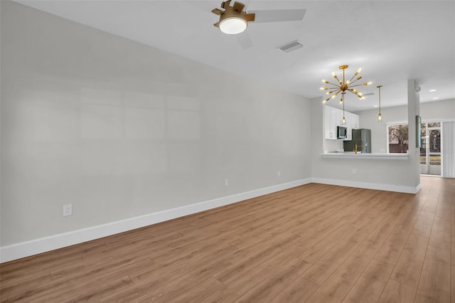 unfurnished living room with light wood finished floors, baseboards, visible vents, and ceiling fan with notable chandelier