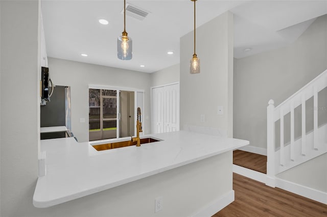 kitchen featuring visible vents, stainless steel microwave, a sink, a peninsula, and fridge