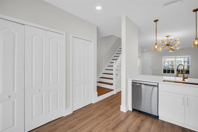 kitchen with a sink, visible vents, white cabinets, dishwasher, and light wood finished floors