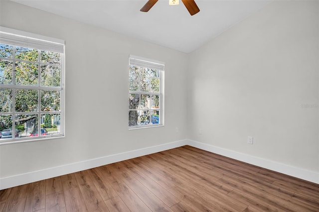 unfurnished room featuring lofted ceiling, wood finished floors, a ceiling fan, and baseboards