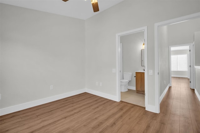 unfurnished bedroom with ceiling fan, wood finished floors, connected bathroom, and baseboards