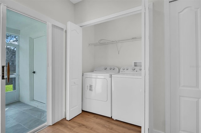 laundry room with laundry area, washing machine and dryer, and light wood-style floors