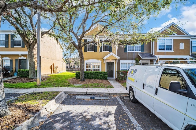 view of property featuring uncovered parking and stucco siding