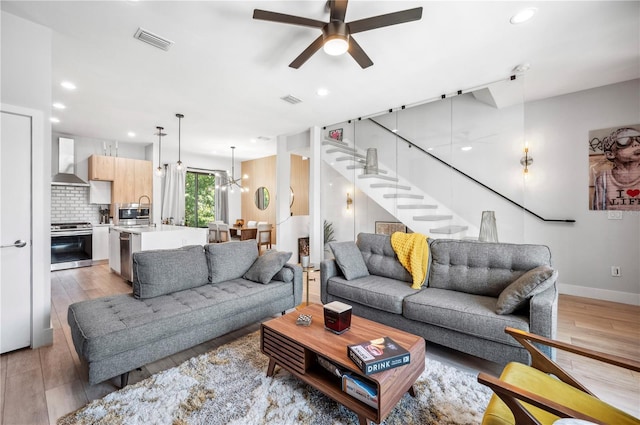 living area with ceiling fan with notable chandelier, light wood-type flooring, visible vents, and recessed lighting