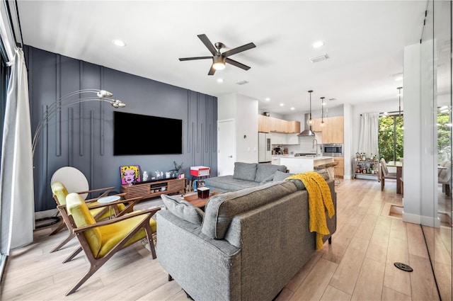 living room featuring light wood-style floors, recessed lighting, visible vents, and a ceiling fan