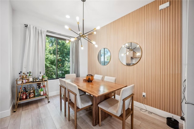 dining room featuring light wood-style flooring, a chandelier, and baseboards