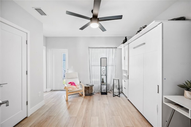 sitting room with visible vents, ceiling fan, light wood-style flooring, and baseboards