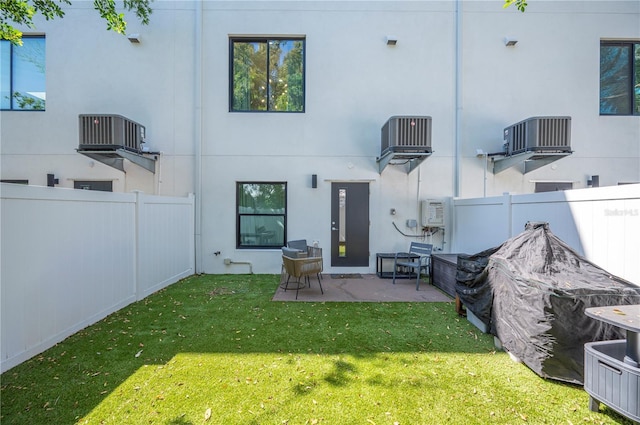 rear view of house featuring a yard, a patio area, a fenced backyard, and stucco siding