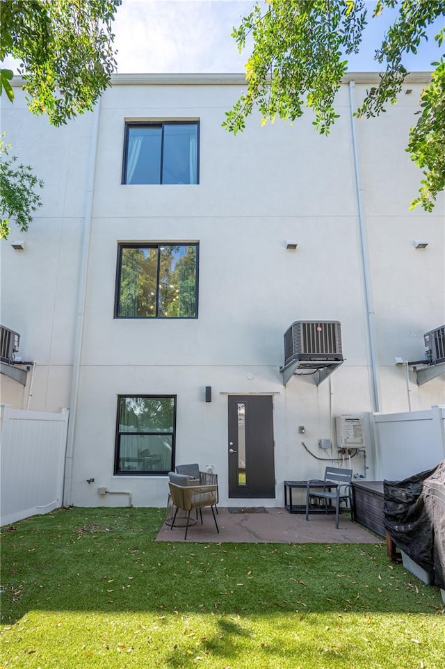 rear view of house featuring a yard, a patio area, and stucco siding