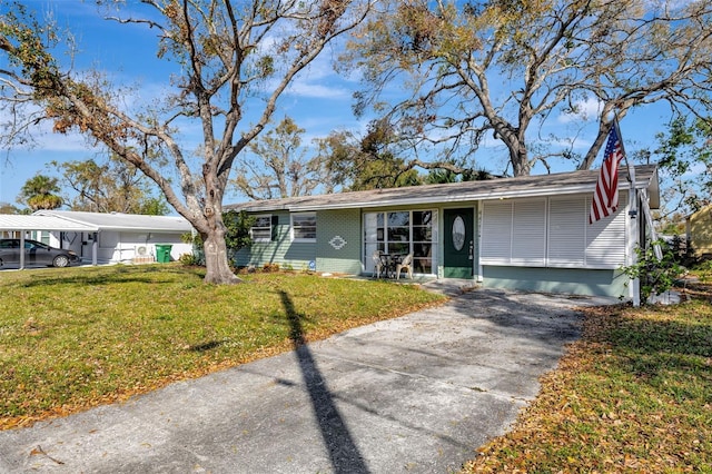 single story home with a carport, a front yard, brick siding, and driveway