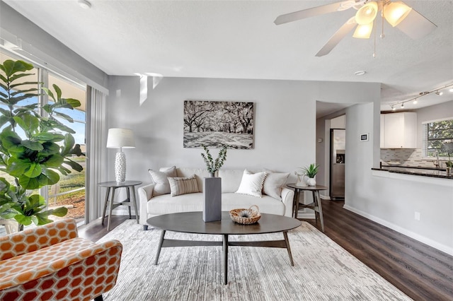 living room with dark wood-style floors, a textured ceiling, and baseboards