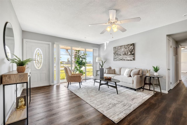 living room with a textured ceiling, dark wood-style flooring, a ceiling fan, and baseboards