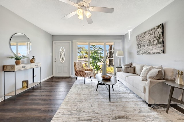 living room featuring baseboards, a textured ceiling, a ceiling fan, and wood finished floors