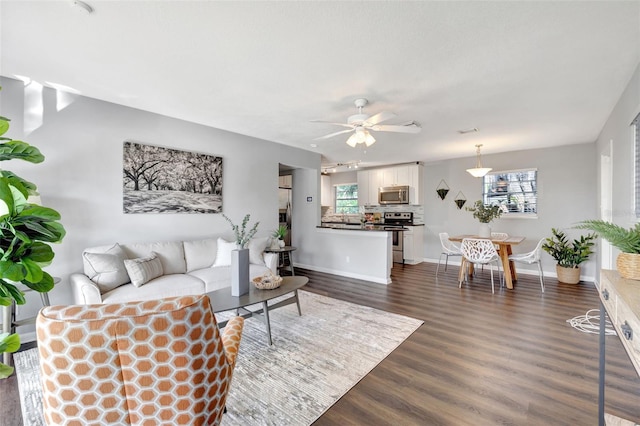 living room featuring dark wood-style flooring, ceiling fan, and baseboards