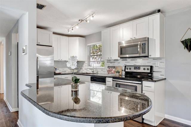 kitchen featuring stainless steel appliances, a sink, white cabinetry, and decorative backsplash