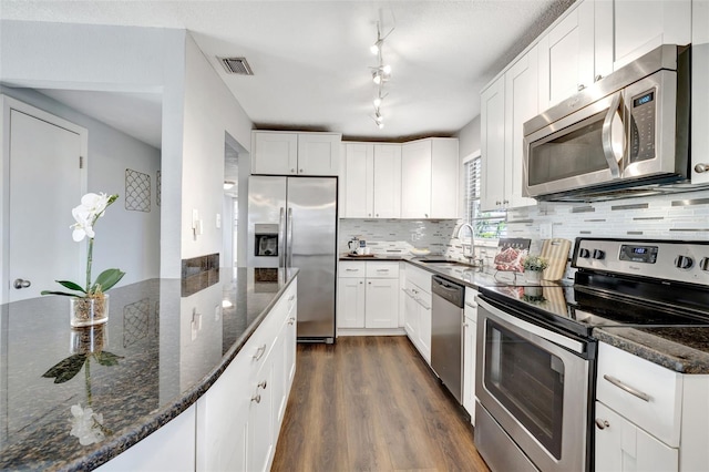 kitchen with visible vents, dark stone counters, appliances with stainless steel finishes, dark wood-type flooring, and a sink