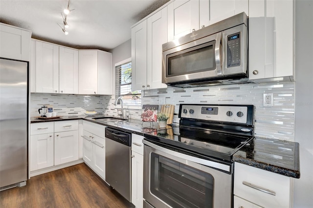 kitchen featuring dark wood finished floors, stainless steel appliances, backsplash, white cabinets, and a sink