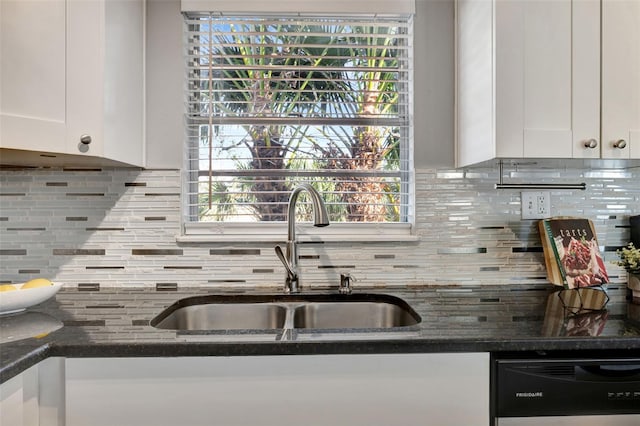 kitchen with dark stone counters, a sink, white cabinetry, backsplash, and dishwasher