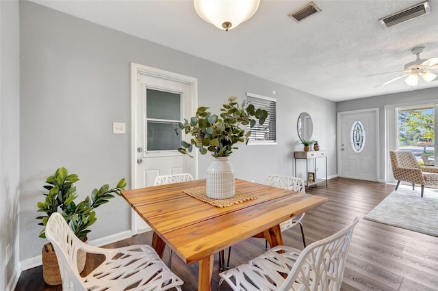 dining area featuring baseboards, a textured ceiling, visible vents, and wood finished floors