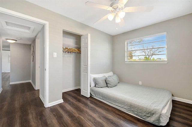 bedroom with a closet, attic access, ceiling fan, wood finished floors, and baseboards