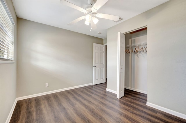 unfurnished bedroom with dark wood-style floors, a closet, and baseboards