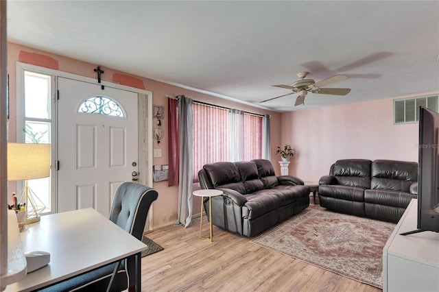 living area featuring light wood-type flooring, a healthy amount of sunlight, visible vents, and ceiling fan