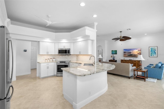 kitchen with a peninsula, arched walkways, a sink, appliances with stainless steel finishes, and open floor plan