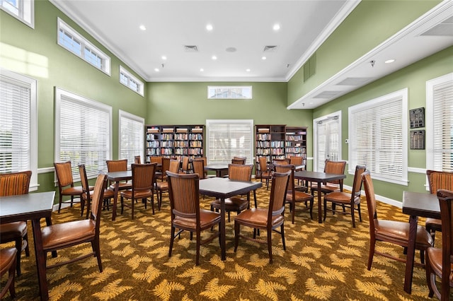 dining room featuring crown molding, visible vents, baseboards, and a towering ceiling