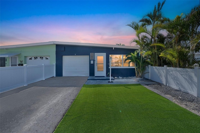 view of front facade with a yard, an attached garage, fence, and driveway