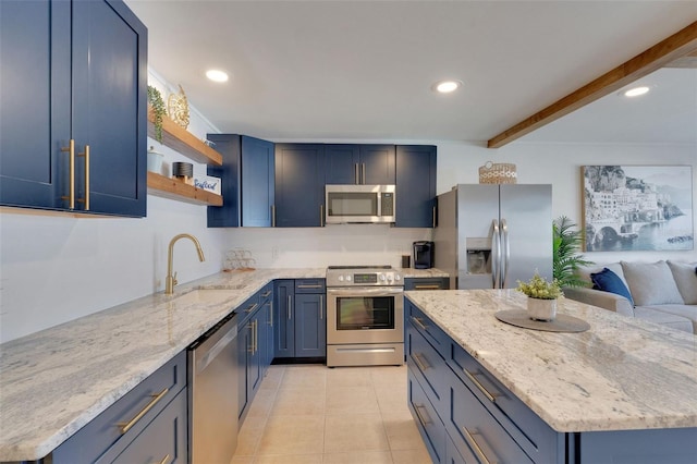 kitchen with stainless steel appliances, a sink, blue cabinetry, and light stone countertops