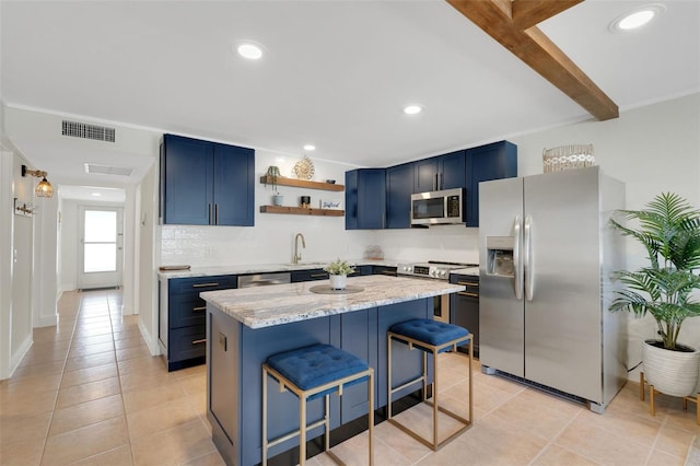 kitchen with blue cabinets, visible vents, a kitchen breakfast bar, appliances with stainless steel finishes, and tasteful backsplash