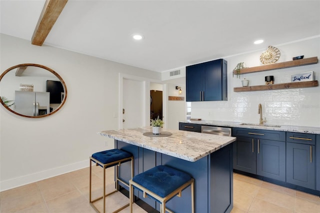 kitchen with light stone counters, a breakfast bar, blue cabinets, stainless steel appliances, and a sink