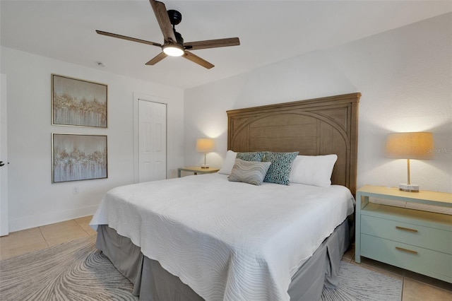 bedroom with a ceiling fan, a closet, baseboards, and light tile patterned floors