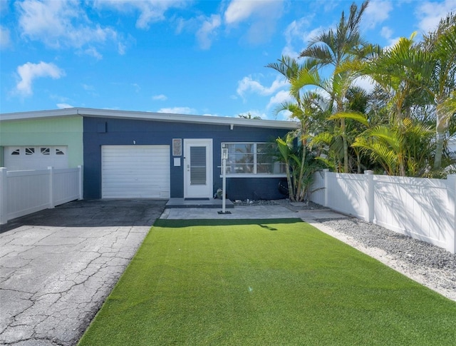 view of front of home featuring a garage, driveway, fence, and a front yard