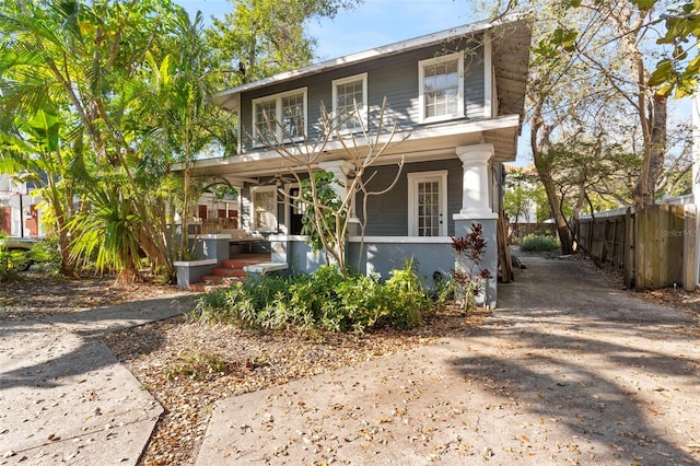 view of front of house featuring a balcony, covered porch, driveway, and fence