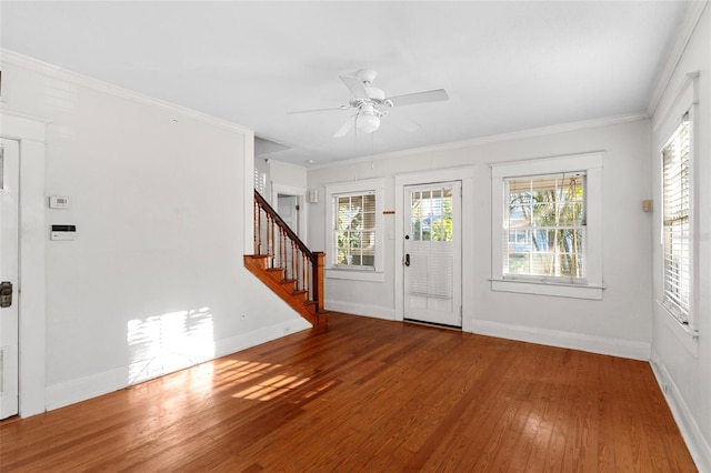 entrance foyer with wood-type flooring, stairway, baseboards, and ornamental molding