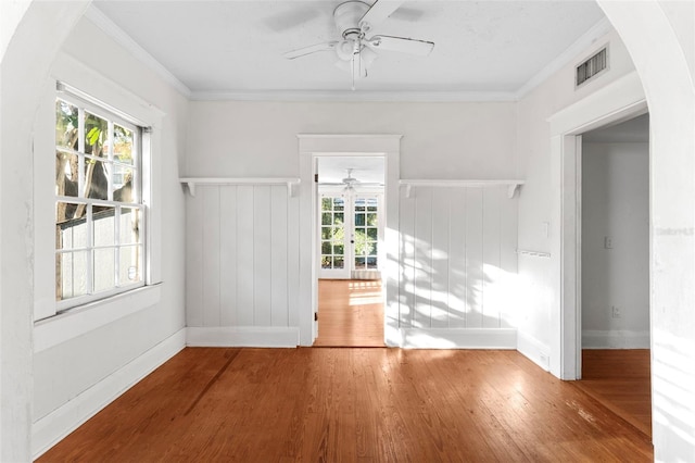 spare room featuring ceiling fan, visible vents, crown molding, and wood finished floors