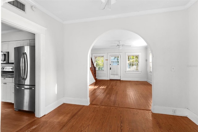 entrance foyer with visible vents, arched walkways, ceiling fan, ornamental molding, and hardwood / wood-style floors